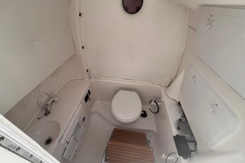 Slide: The Image of 2017 Tidewater 280 CC Adventure boat bathroom with toilet, sink, and storage compartments. - 25