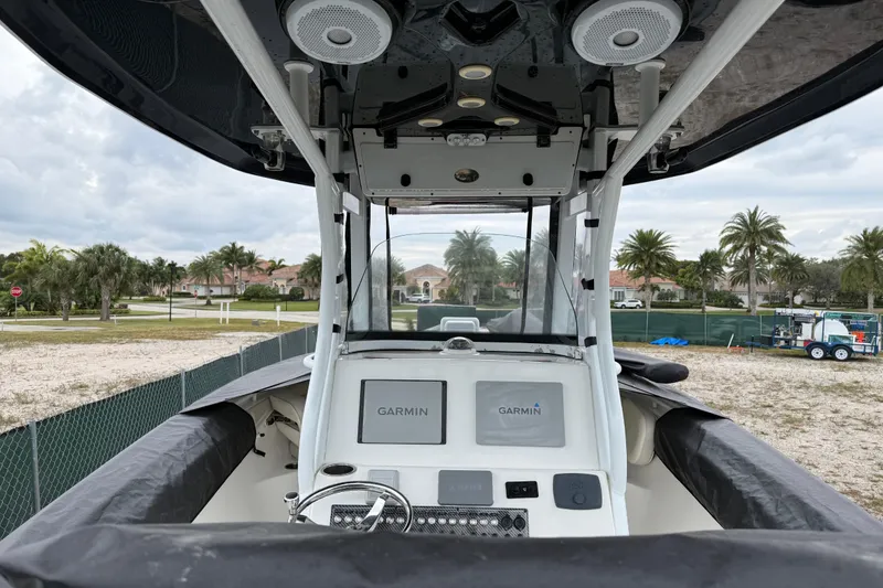 Slide: The Image of 2017 Tidewater 280 CC Adventure boat cockpit with Garmin displays, parked near palm trees. - 7