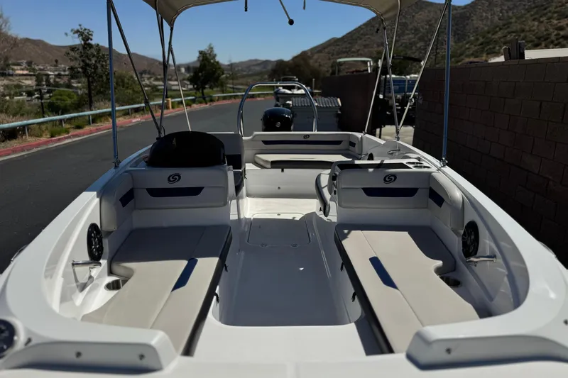Slide: The Image of 2022 Hurricane SunDeck Sport 185 OB boat interior with seating and canopy, parked outdoors. - 9