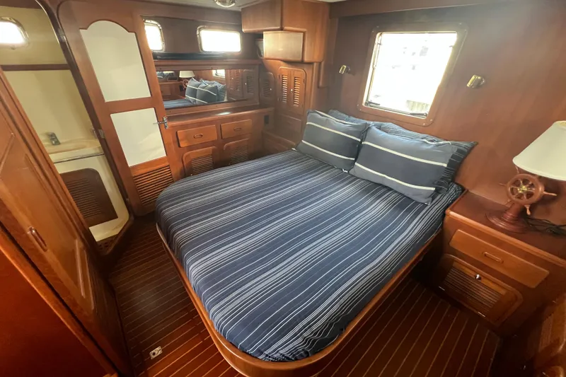 Slide: The Image of Cozy bedroom in 2007 Heritage East Sundeck Trawler with wooden interior and striped bedding. - 12