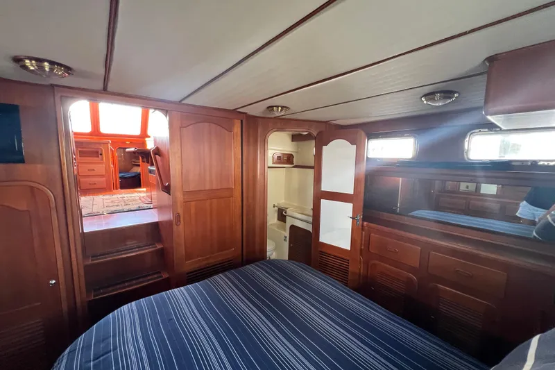 Slide: The Image of Luxurious 2007 Heritage East Sundeck Trawler cabin with wood interior and striped bedding. - 13