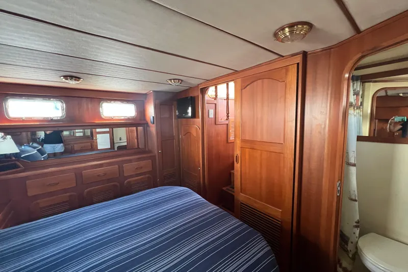 Slide: The Image of Luxurious 2007 Heritage East Sundeck Trawler cabin with wooden interior and striped bedding. - 14