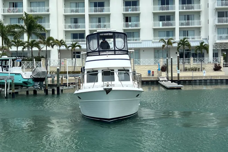 Slide: The Image of 2007 Heritage East Sundeck Trawler docked near waterfront building with palm trees. - 2