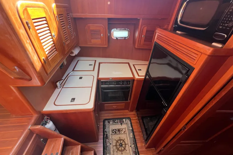 Slide: The Image of 2007 Heritage East Sundeck Trawler kitchen with wood cabinetry, stove, and microwave. - 21
