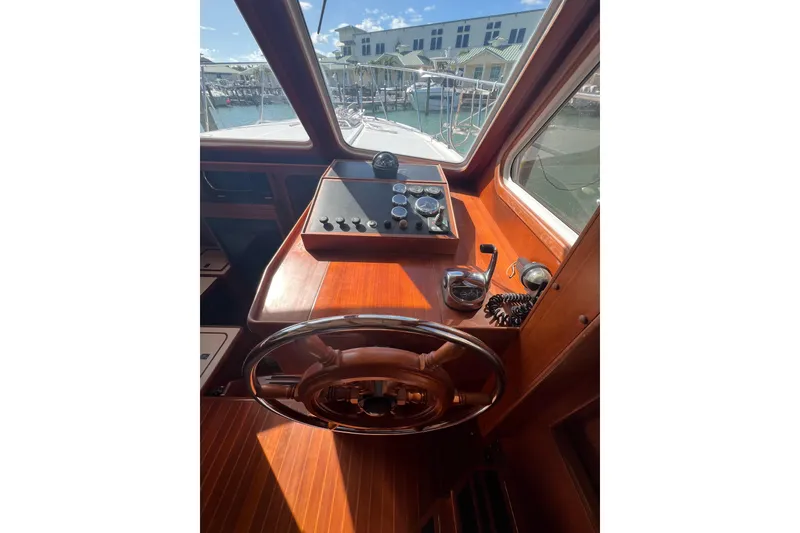 Slide: The Image of 2007 Heritage East Sundeck Trawler helm with wooden steering wheel and control panel. - 25