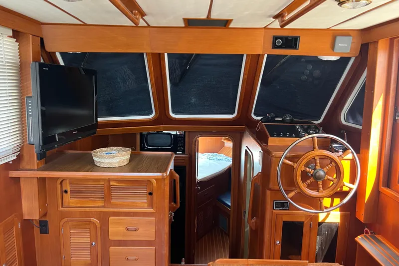 Slide: The Image of 2007 Heritage East Sundeck Trawler interior with wooden helm, TV, and cozy cabin. - 33