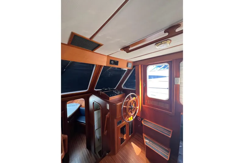 Slide: The Image of 2007 Heritage East Sundeck Trawler interior with wooden helm and seating area. - 34
