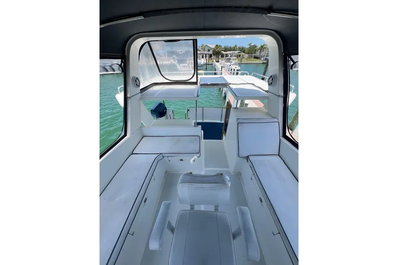 Slide: The Image of Interior view of 2007 Heritage East Sundeck Trawler with white seating and marina backdrop. - 5