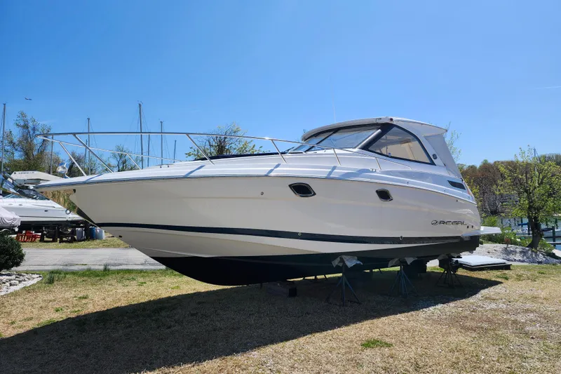 The Image of 2019 Regal 35 Sport Coupe boat on land under clear blue sky. - 0