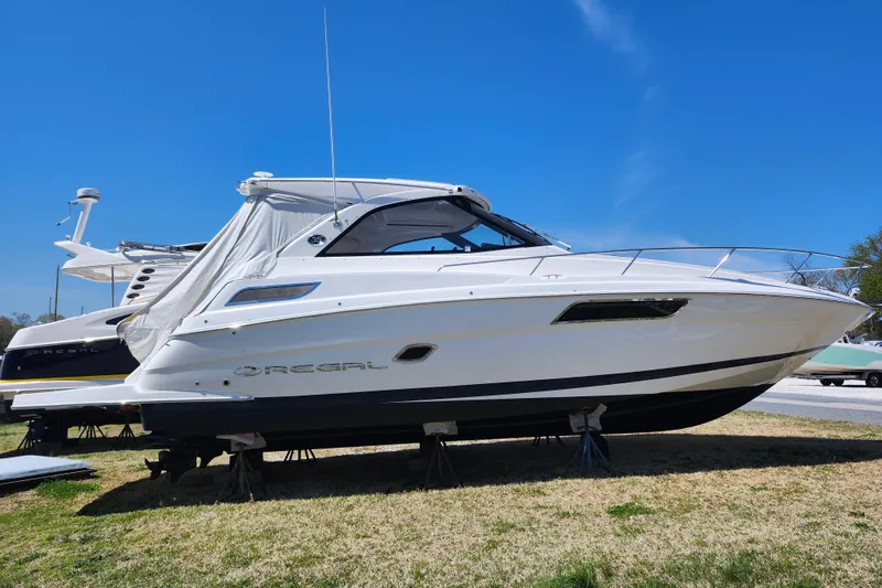 Slide: The Image of 2019 Regal 35 Sport Coupe boat on stands under clear blue sky. - 3