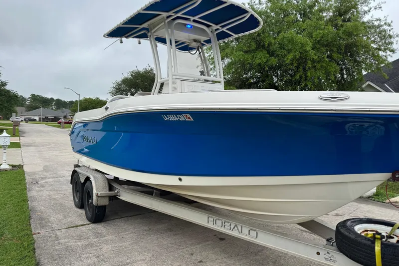 Slide: The Image of 2017 Robalo R200 Center Console boat on trailer, blue hull, parked in residential area. - 11