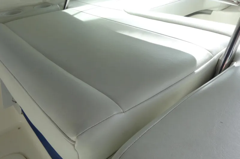 Slide: The Image of 2007 Bayliner 285 boat interior with white cushioned seating and cup holders. - 14