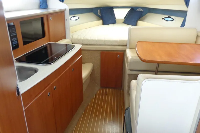 Slide: The Image of 2007 Bayliner 285 interior with kitchenette, dining area, and cozy sleeping quarters. - 21
