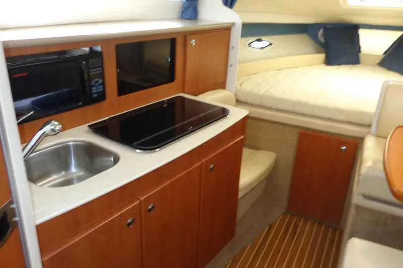 Slide: The Image of 2007 Bayliner 285 interior with kitchenette, sink, stove, and cozy sleeping area. - 22