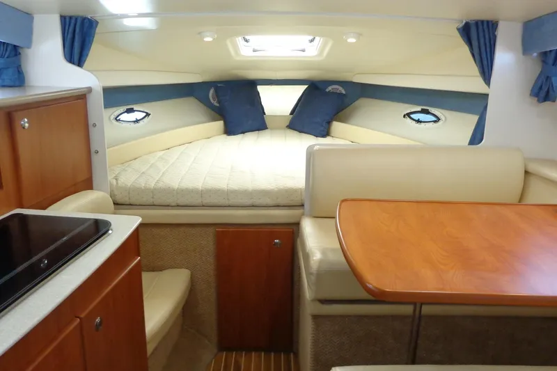 Slide: The Image of 2007 Bayliner 285 cabin interior with bed, dining area, and kitchenette. - 23