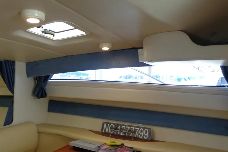 Slide: The Image of Interior of a 2007 Bayliner 285 boat with blue curtains and beige seating. - 30