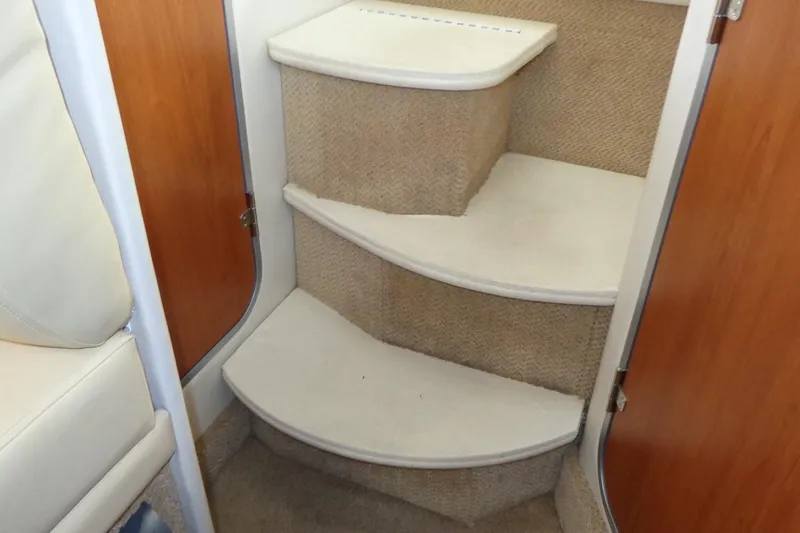 Slide: The Image of Interior stairs of a 2007 Bayliner 285 boat, featuring carpeted steps and wooden paneling. - 35