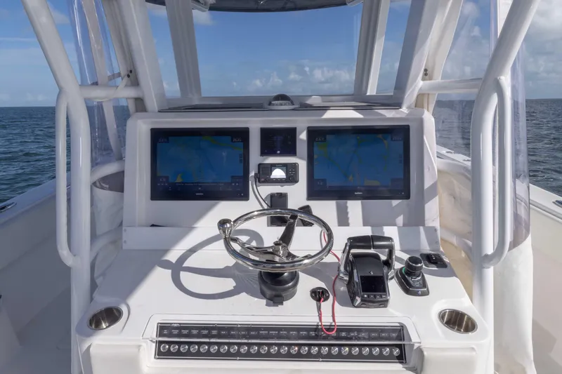 Slide: The Image of 2023 Invincible 35 Catamaran helm with dual screens and steering wheel on open water. - 31