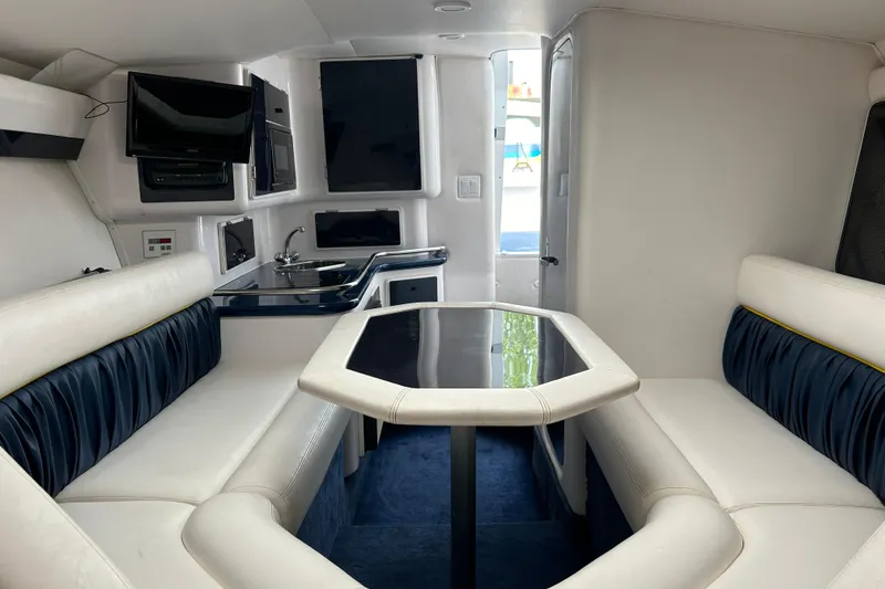 Slide: The Image of Interior of a 2001 Donzi boat featuring white seating, a kitchenette, and a mounted TV. - 32