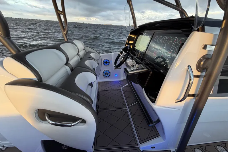 Slide: The Image of 2021 Nor-Tech 390 Sport Center Console interior with modern dashboard and seating, overlooking the ocean. - 11