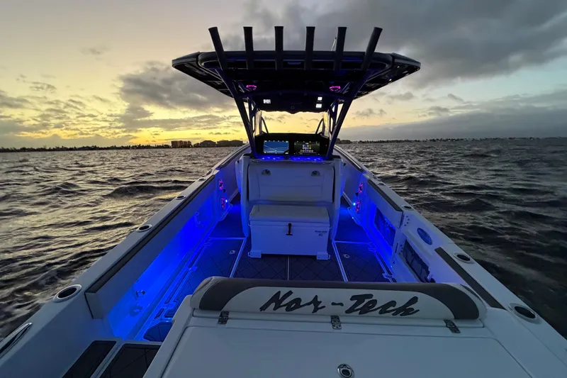 Slide: The Image of 2021 Nor-Tech 390 Sport Center Console boat at sunset with blue interior lighting. - 25
