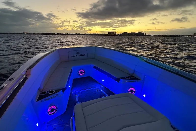 Slide: The Image of 2021 Nor-Tech 390 Sport Center Console boat with blue LED lights at sunset. - 26