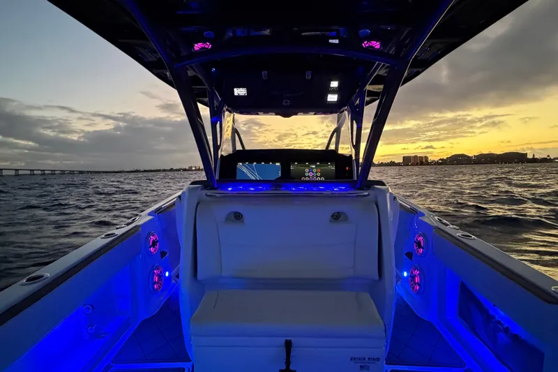 Slide: The Image of 2021 Nor-Tech 390 Sport Center Console at sunset, featuring illuminated interior and ocean view. - 27