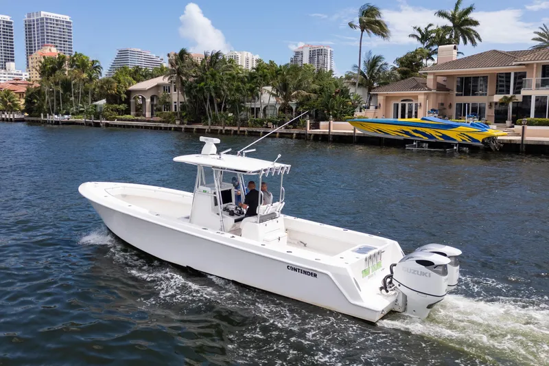 Slide: The Image of 2014 Contender 35 ST boat cruising on a scenic waterfront with luxury homes. - 2