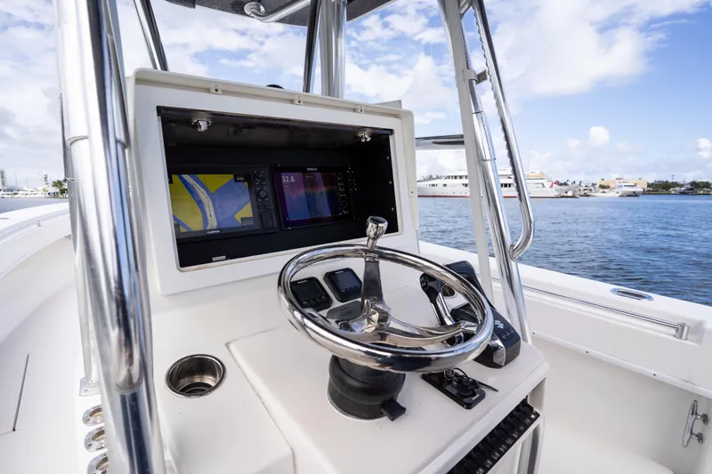 Slide: The Image of 2014 Contender 35 ST boat helm with navigation screens and steering wheel, docked by the water. - 22