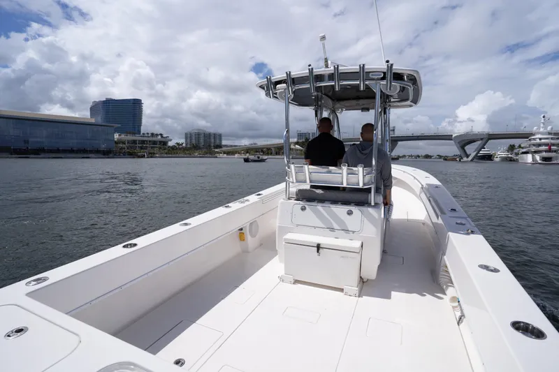 Slide: The Image of 2014 Contender 35 ST boat cruising in a scenic waterfront area with modern buildings. - 27