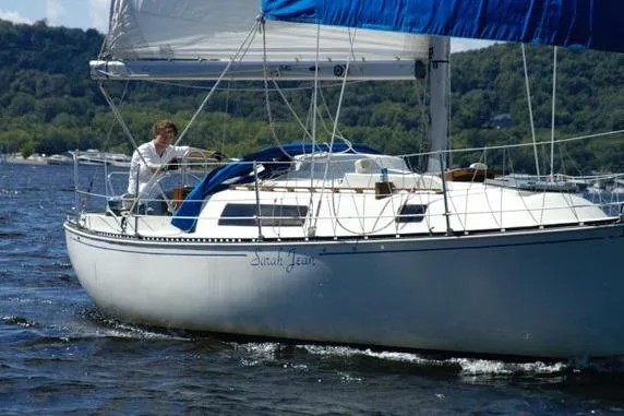 The Image of 1980 C&C 30 Mk I sailboat navigating on a scenic lake with lush green hills. - 1