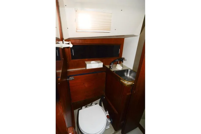 Slide: The Image of 1980 C&C 30 Mk I yacht bathroom with wooden cabinetry, sink, and toilet. - 12
