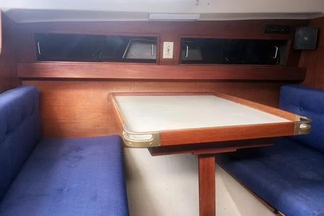 Slide: The Image of Interior of 1980 C&C 30 Mk I sailboat with wooden table and blue cushioned seating. - 8