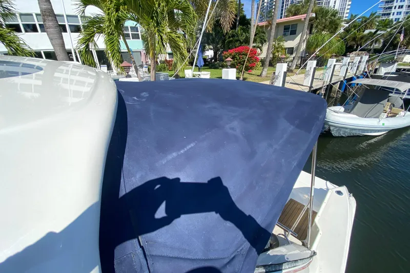 Slide: The Image of 2008 Sea Ray Sundancer 330 with blue cover docked near palm trees and waterfront homes. - 19
