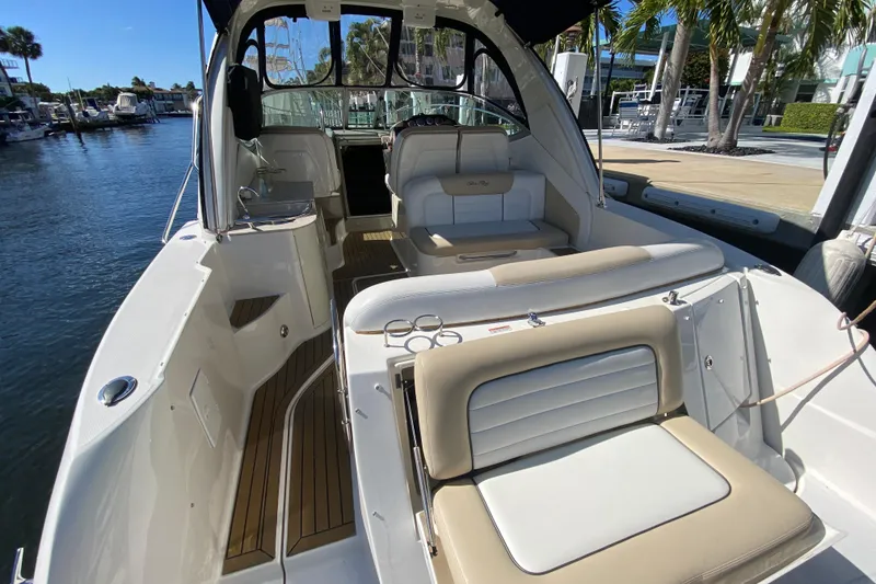 Slide: The Image of 2008 Sea Ray Sundancer 330 yacht interior with seating, docked by palm trees. - 23