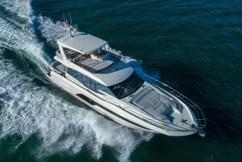 Slide: The Image of Prestige 590 yacht 2020 model cruising on open water with a person at the helm. - 6