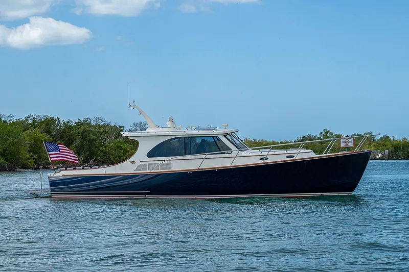 The Image of 2021 Hinckley Talaria 43 yacht cruising on a serene waterway under a clear blue sky. - 0