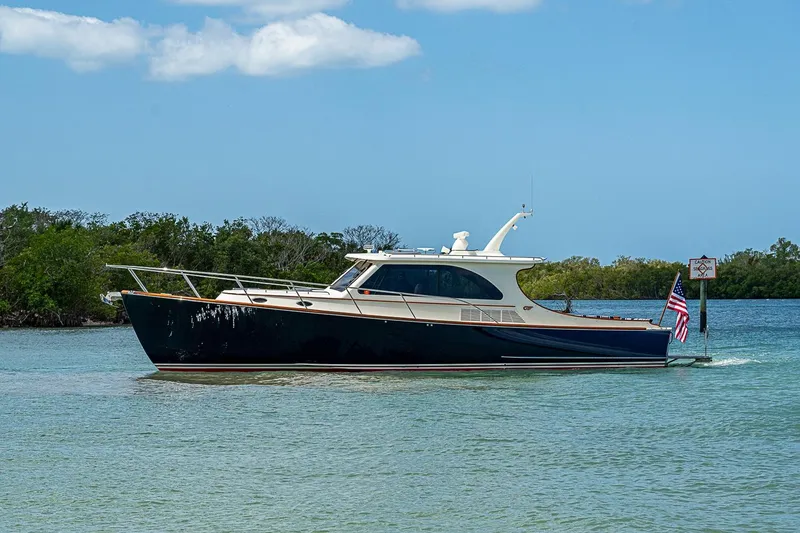 Slide: The Image of 2021 Hinckley Talaria 43 yacht cruising on a serene waterway under a clear blue sky. - 13