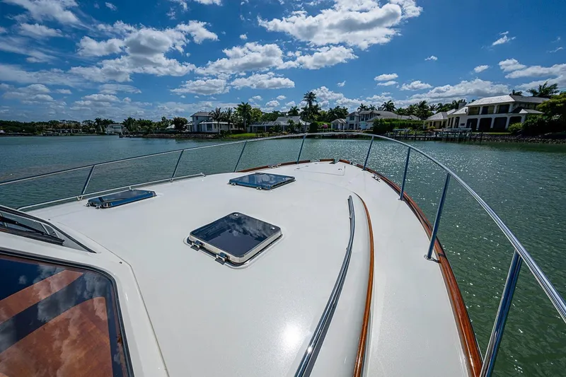 Slide: The Image of Hinckley Talaria 43 yacht deck, 2021 model, cruising near waterfront homes under a blue sky. - 22