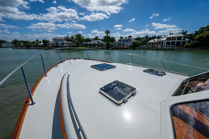 Slide: The Image of Hinckley Talaria 43 yacht deck, 2021 model, cruising near waterfront homes under a blue sky. - 25