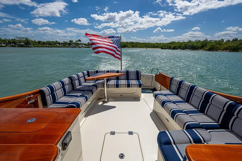 Slide: The Image of Hinckley Talaria 43 yacht deck with striped seating, American flag, and scenic water view. - 26