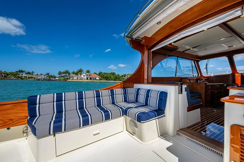 Slide: The Image of Hinckley Talaria 43 yacht interior with striped seating, overlooking serene waterfront homes. - 28