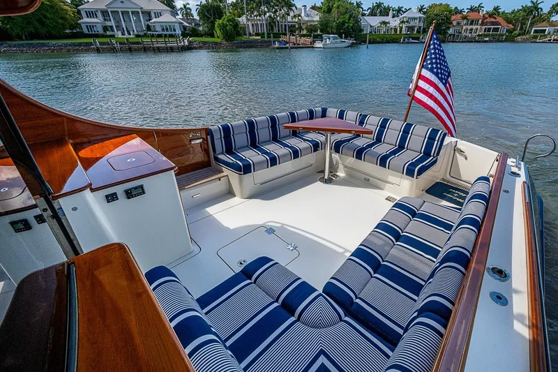 Slide: The Image of Luxurious 2021 Hinckley Talaria 43 yacht with striped seating and American flag on calm water. - 31