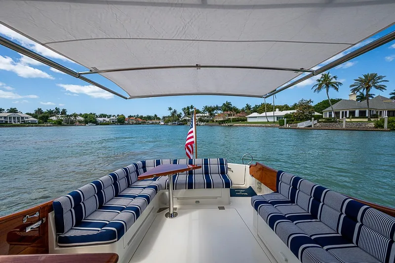 Slide: The Image of Hinckley Talaria 43 yacht interior with striped seating, overlooking serene waterfront homes. - 33