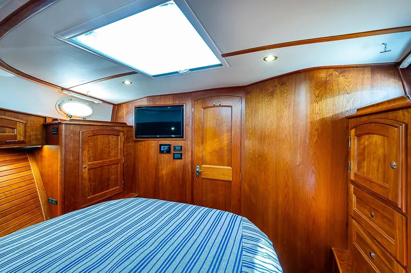 Slide: The Image of Luxurious 2021 Hinckley Talaria 43 cabin interior with wood paneling and striped bedding. - 39