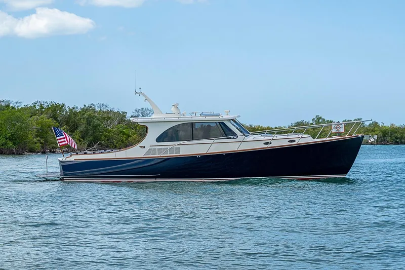 Slide: The Image of 2021 Hinckley Talaria 43 yacht cruising on calm waters with lush greenery in the background. - 4