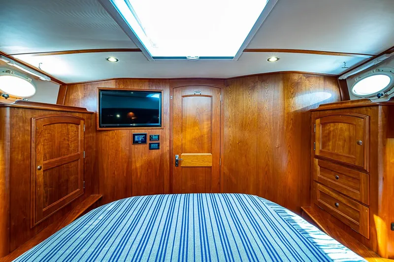 Slide: The Image of Luxurious 2021 Hinckley Talaria 43 cabin interior with wood paneling and striped bedding. - 40