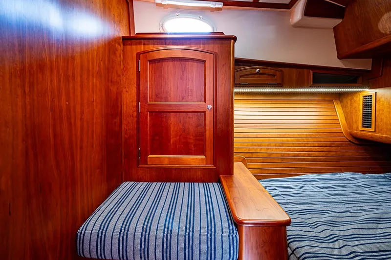 Slide: The Image of Interior of 2021 Hinckley Talaria 43 yacht with wooden paneling and striped bedding. - 43