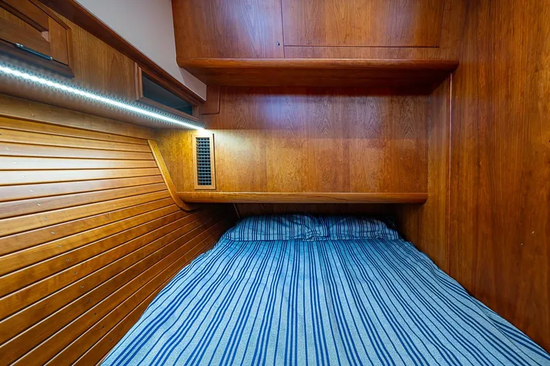 Slide: The Image of Cozy wooden cabin interior of 2021 Hinckley Talaria 43 with striped bedding. - 44