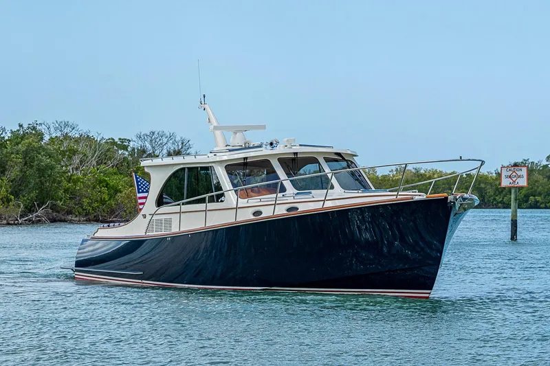 Slide: The Image of 2021 Hinckley Talaria 43 yacht cruising on calm waters near lush greenery. - 7